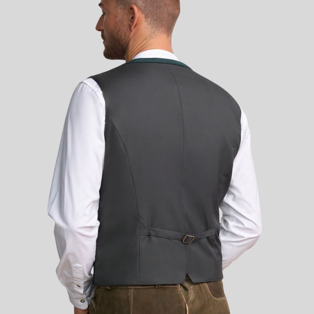 Man wearing a gray vest over a white shirt on a plain background