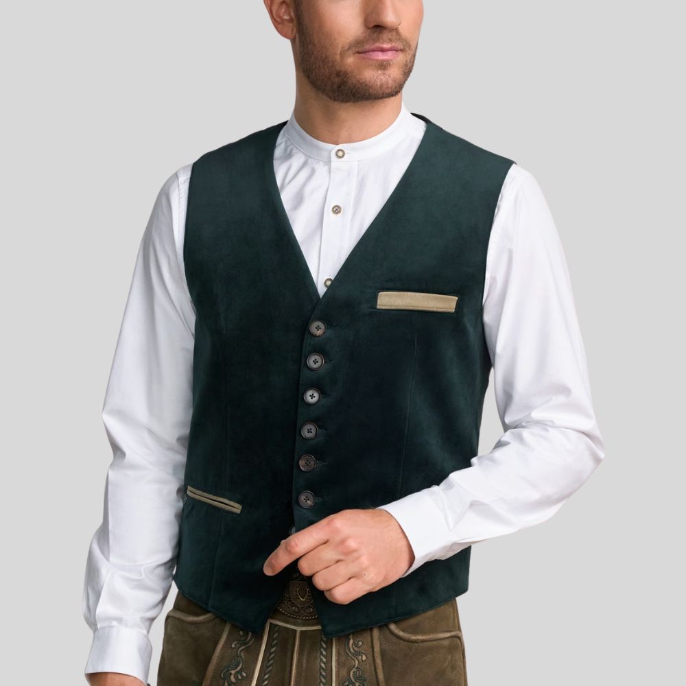 Man wearing a dark green vest over a white shirt on a gray background