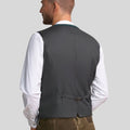 Man wearing a gray vest over a white shirt on a plain background