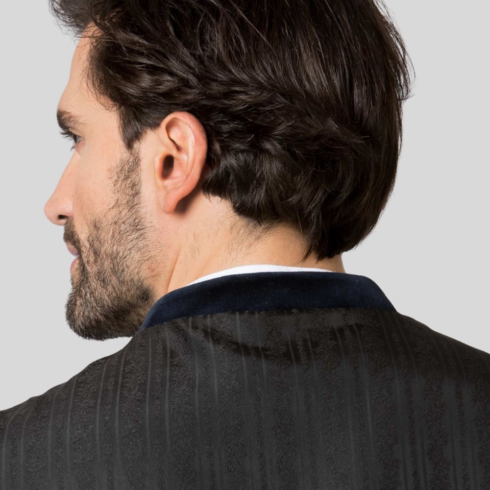 Man wearing a dark suit jacket with a light gray background