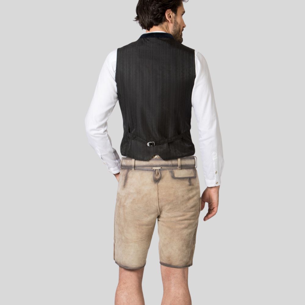 Man wearing a black vest, white shirt, and beige shorts on a light gray background